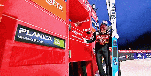 a skier wearing a number 22 jersey stands in front of a planica advertisement