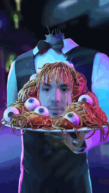 a man is holding a tray of spaghetti and eyeballs
