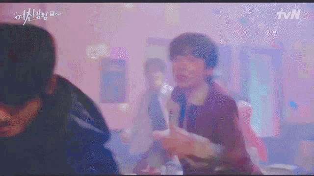 a group of people are dancing in a room with a purple light .