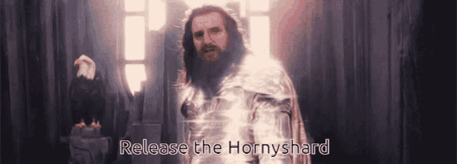 a man with a beard is standing in front of a window with the words release the hornyshard written below him
