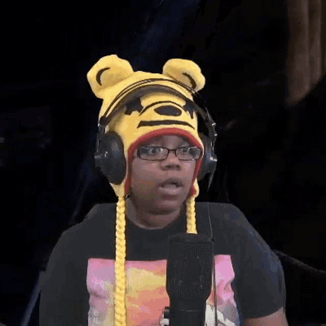 a person wearing a winnie the pooh hat and headphones talking into a microphone