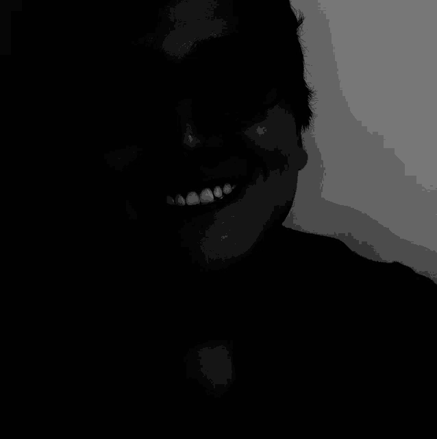 a black and white photo of a man smiling with his mouth open