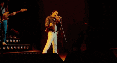 a man in a leather jacket singing into a microphone on stage
