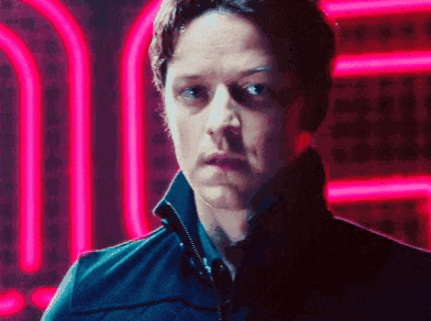 a man in a black jacket stands in front of a neon sign that says u
