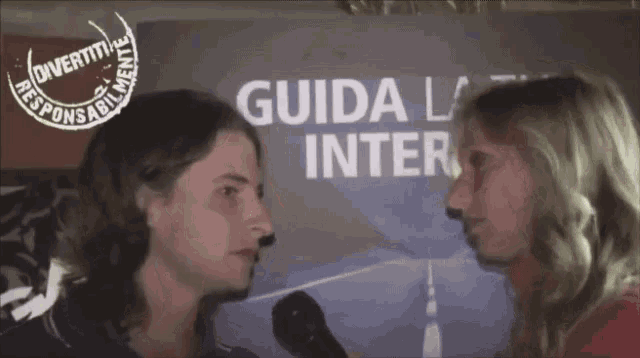 a man and woman are talking in front of a sign that says " guida la inter "