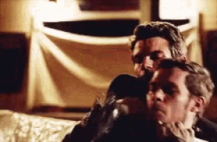 two men are sitting next to each other on a couch in a room .