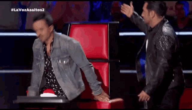 two men are giving each other a high five while sitting in a chair