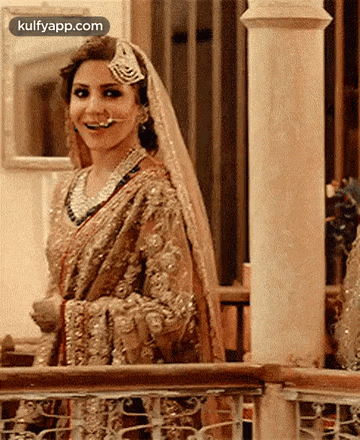 a woman in a wedding dress is standing next to a railing and smiling .
