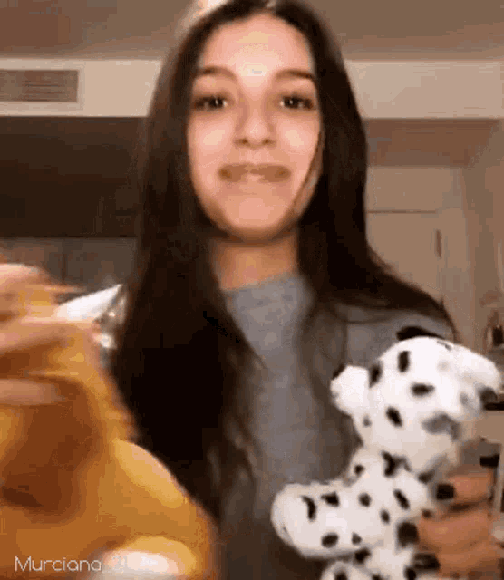 a woman is holding a stuffed dalmatian dog in her hands while smiling .