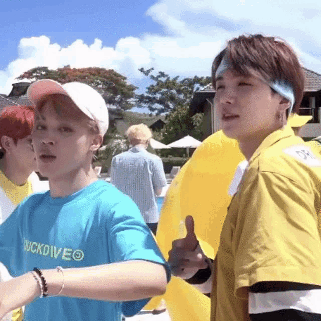 a man in a yellow shirt is giving a thumbs up next to another man in a blue shirt .