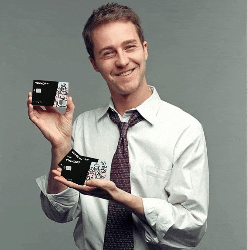 a man in a white shirt and tie holds up two timkoff cards