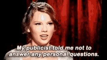 a woman is standing in front of a red curtain and talking to someone .