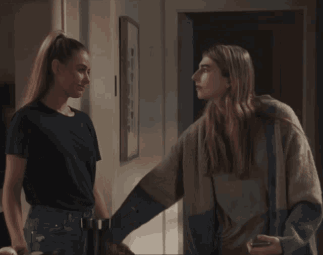 two women are standing next to each other and one is holding another 's hand