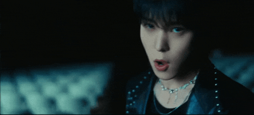 a close up of a person wearing a necklace and a black jacket