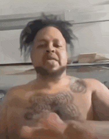 a shirtless man with a tattoo on his chest is taking a selfie .