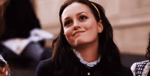 a woman is sitting in a classroom with a yellow headband on her head and smiling .