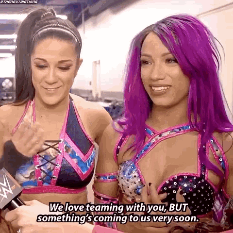 two women with purple hair are smiling and talking to each other