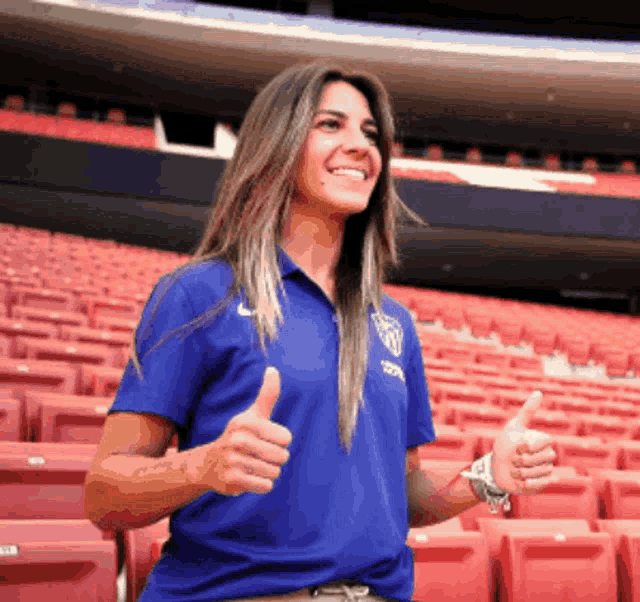 a woman giving a thumbs up in a stadium