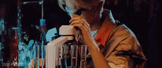 a young man is looking through a microscope in a laboratory .