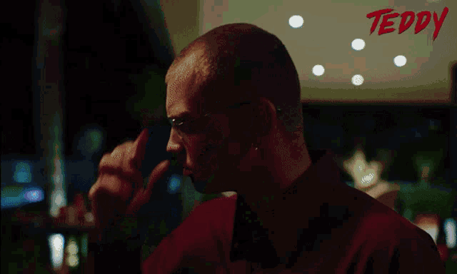 a man in a red shirt is looking at himself in a mirror with the word teddy in red