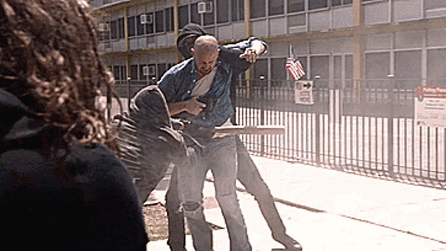 two men are fighting in front of a building with a sign that says polling place on it