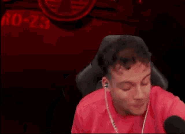 a man wearing headphones and a red shirt is sitting in front of a microphone .