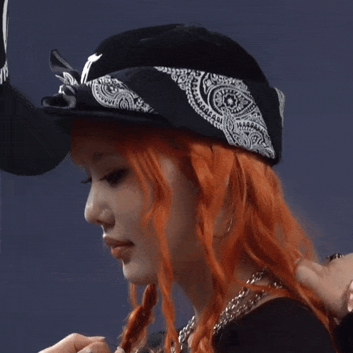 a woman with red hair is wearing a bandana and a baseball cap