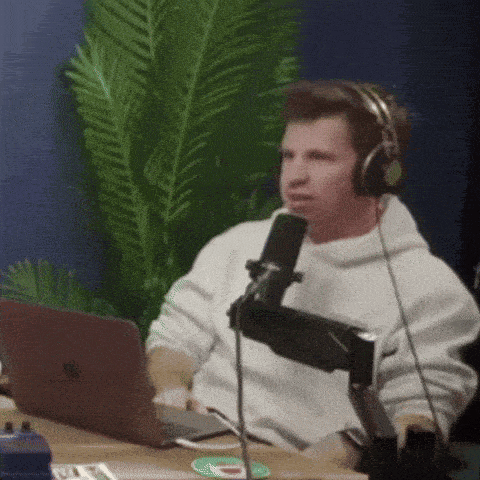 a man wearing headphones is talking into a microphone while using a laptop