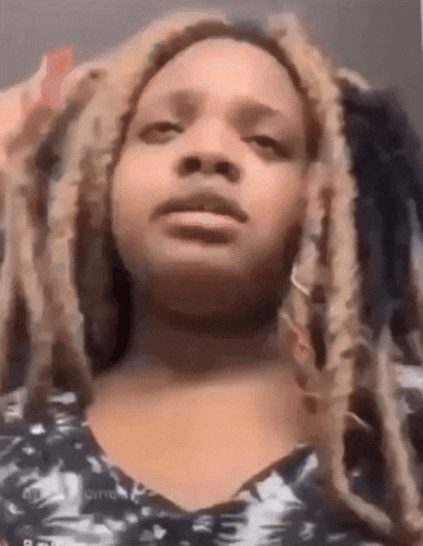 a woman with dreadlocks is making a funny face while looking at the camera .
