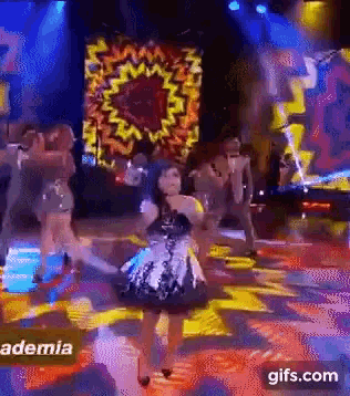 a woman in a dress is dancing on a stage in front of a sign that says aemia