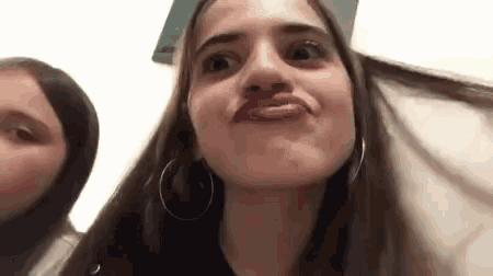 a close up of a woman making a funny face next to another woman .