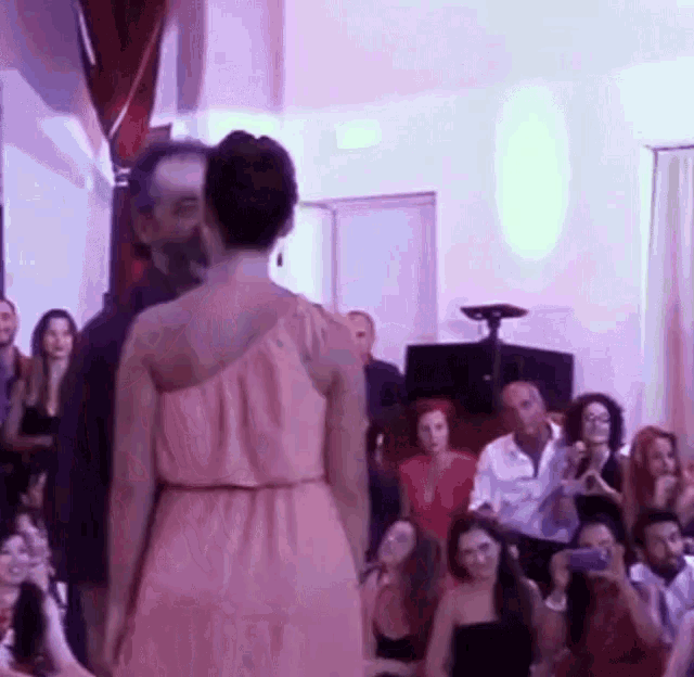 a woman in a pink dress is standing in front of a group of people .