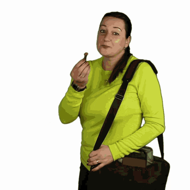 a woman in a yellow sweater is holding a black bag and eating something