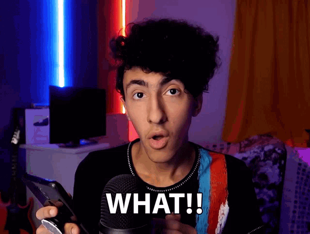 a young man with a surprised look on his face is holding a cell phone and saying what