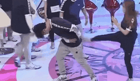 a group of people are dancing on a stage while a woman kicks a man in the face .