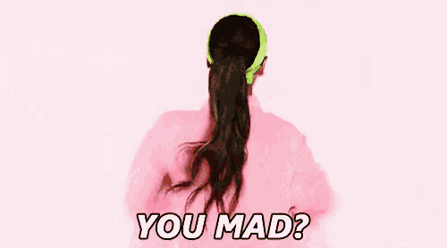 a woman wearing a pink shirt and a green headband is smiling and saying `` you mad ? ''