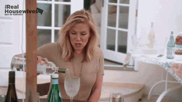 a woman is pouring water into a glass with the words real housewives out of context behind her