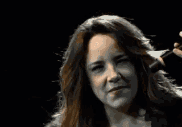 a close up of a woman singing into a microphone with her eyes closed