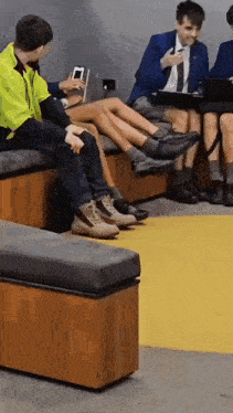 a group of people are sitting on wooden benches with their legs crossed .