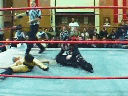 a wrestling match is going on in a ring with a referee in the background