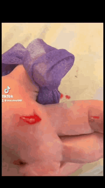a person is holding a purple scrunchie in their hand with blood on it .