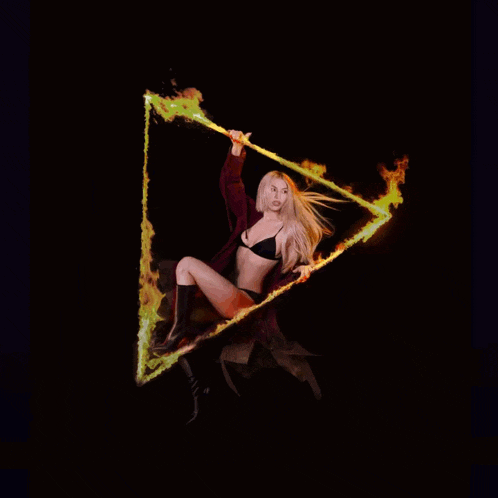 a woman in a black bra is holding a triangle with fire coming out of it
