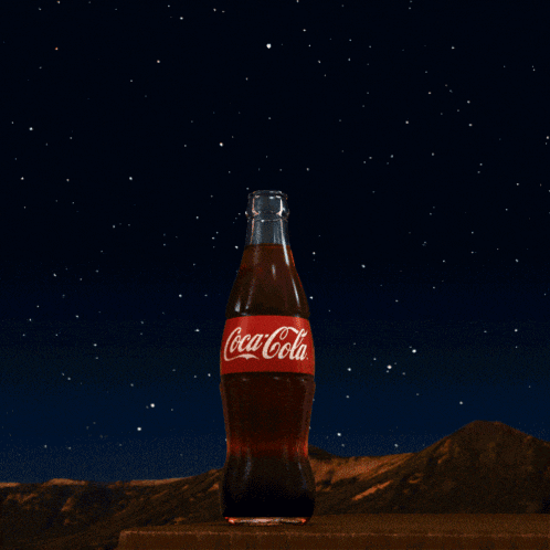 a bottle of coca-cola sits on a table under a starry night sky