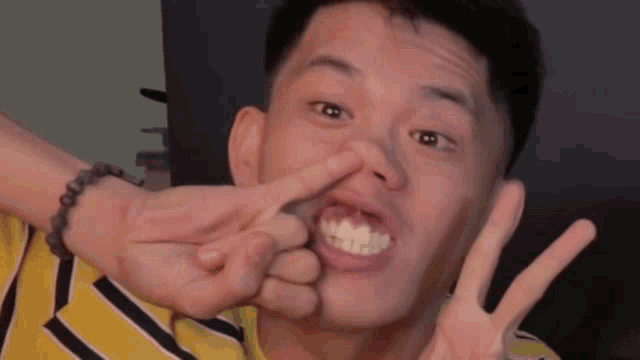 a young man is making a peace sign with his finger in his nose