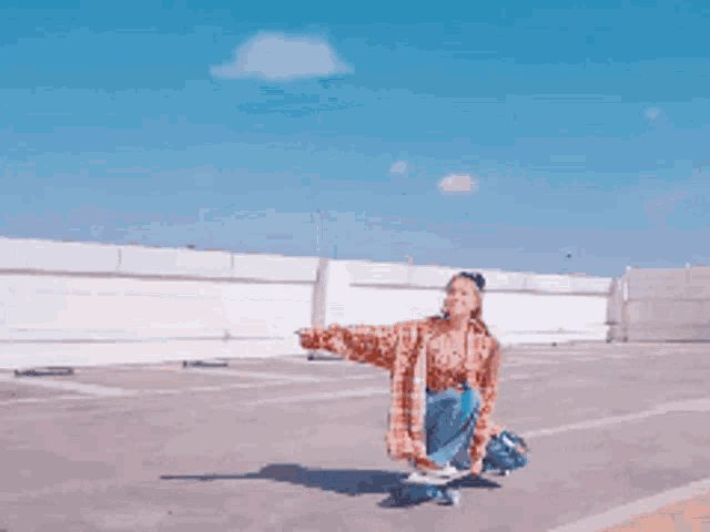 a woman in a plaid shirt is kneeling on a skateboard in a parking lot