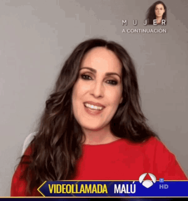 a woman in a red shirt is smiling in front of a screen that says videollamada malu