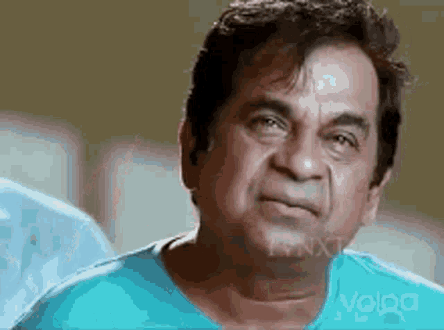 a man in a blue shirt is making a funny face and looking at the camera .