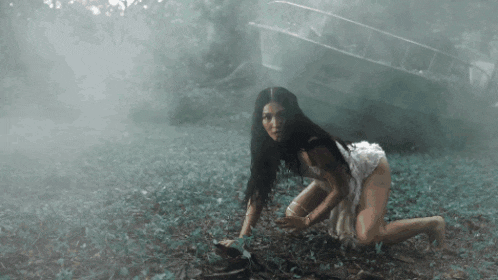 a woman in a white dress is kneeling down in the grass