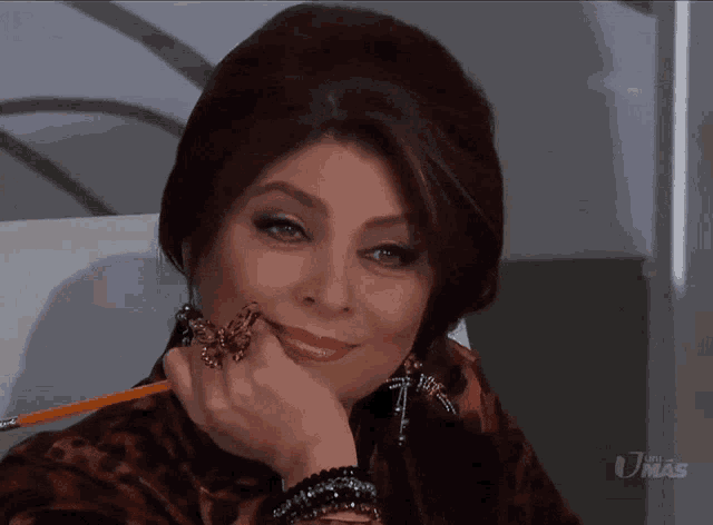 a woman with a ring on her finger is smiling and holding a pencil in her hand