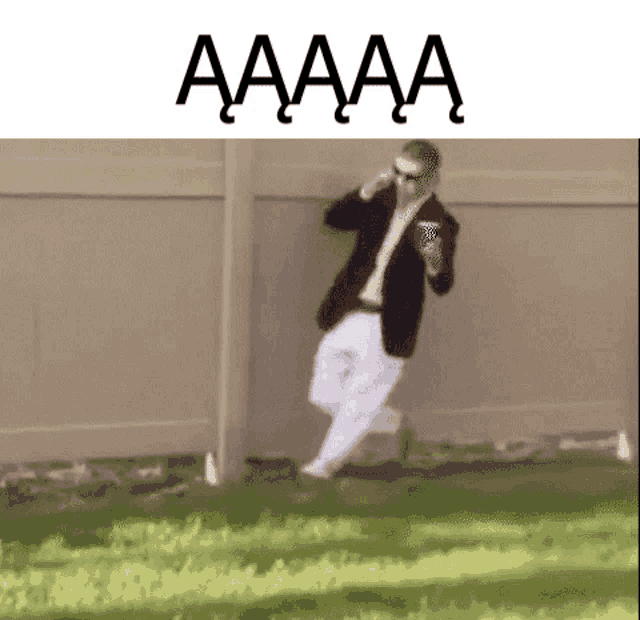 a man in a suit is running towards a fence while holding a blue cup .